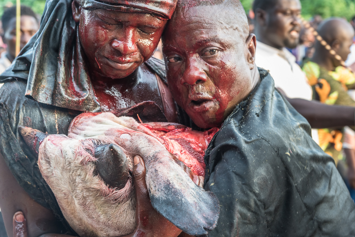 Een priester met zijn zoon helemaal onder het bloed, tijdens een voodoo ritueel in Benin, West-Afrika